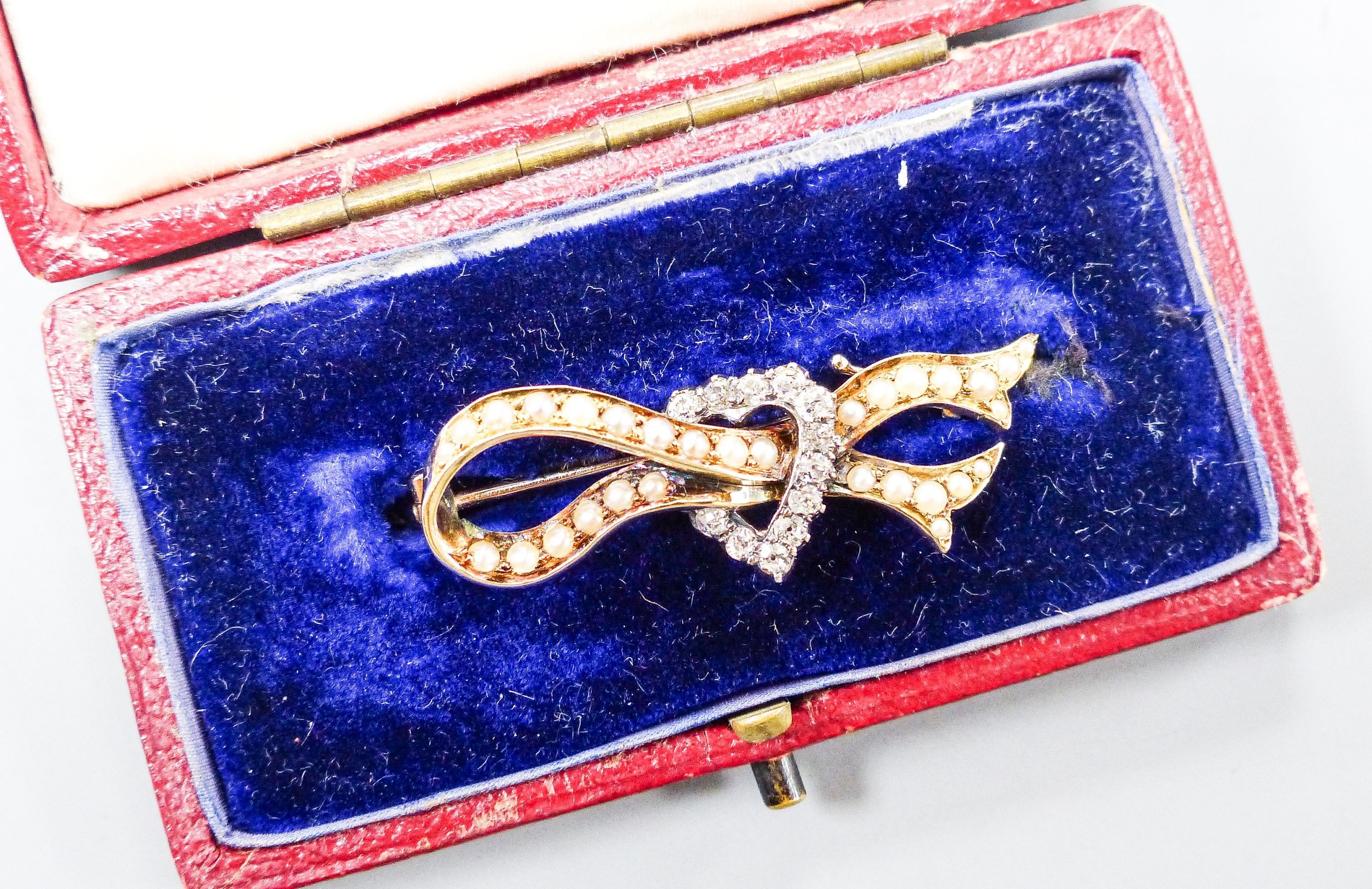 An early 20th century yellow metal, seed pearl and rose cut diamond ribbon and heart brooch, 37mm, gross weight 4.5 grams.